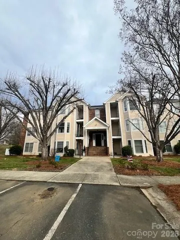 a view of a white house with a large tree in front of it