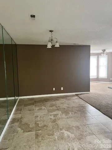 a view of a room with a chandelier fan and wooden floor