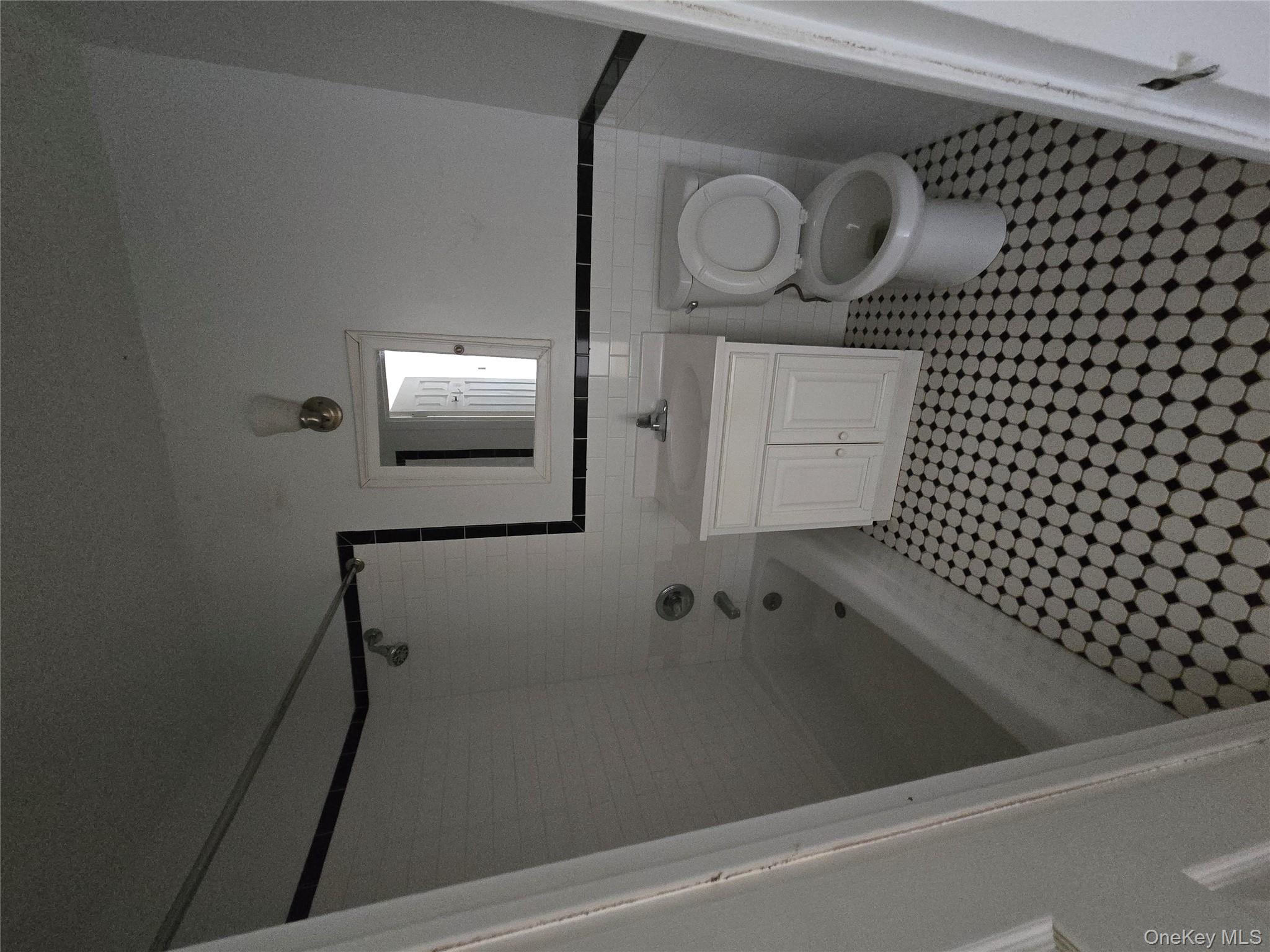 Full bathroom featuring vanity, tile walls, washtub / shower combination, and wainscoting