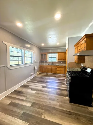 a kitchen with granite countertop wooden cabinets a stove a sink and dishwasher next to a window
