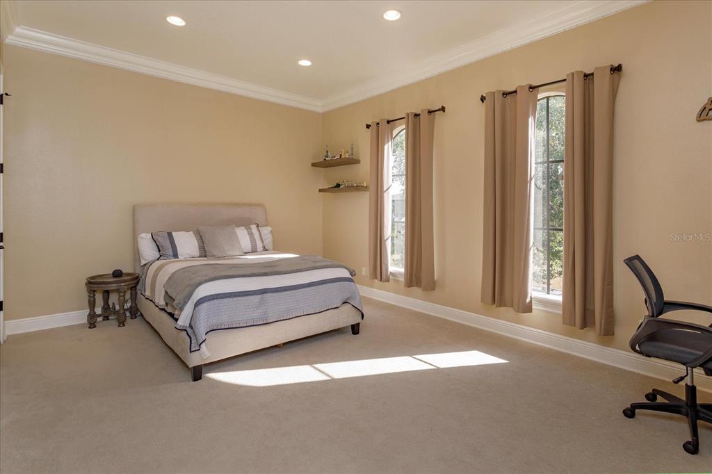 5719 Emerson Pointe Way Orlando, FL 32819 - Photo 35 of 50 a bedroom with a bed chair and a large mirror