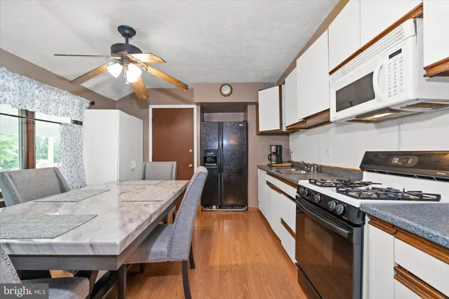 a kitchen with stainless steel appliances granite countertop a stove top oven a sink a dining table and chairs with wooden floor