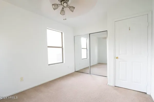 an empty room with a chandelier fan and windows