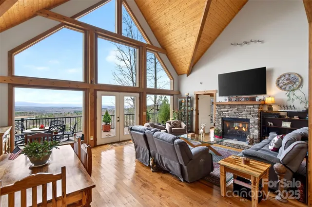 a living room with furniture a fireplace a flat screen tv and a floor to ceiling window