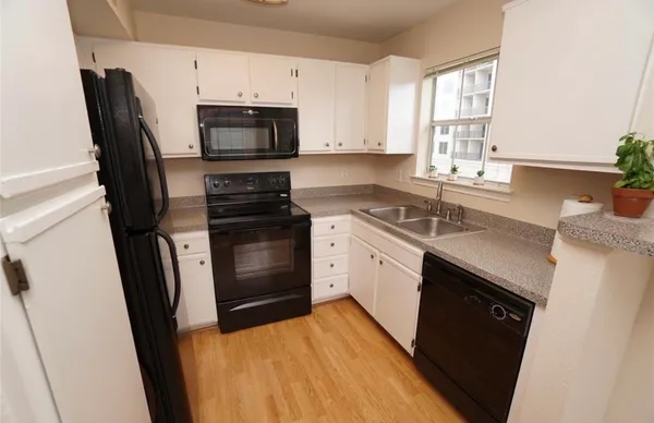 a kitchen with stainless steel appliances granite countertop a sink dishwasher a stove and a microwave oven with cabinets