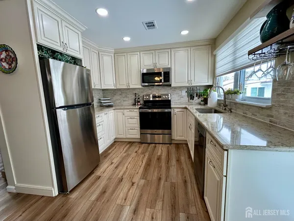 a kitchen with granite countertop stainless steel appliances a refrigerator a sink a stove a microwave and cabinets