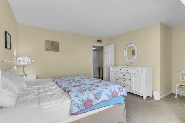 a bedroom with a bed and a lamp on dresser