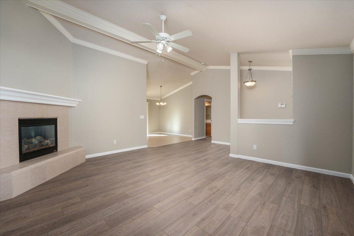 7704 Pit Road Redding, CA 96001 - Photo 7 of 34 an empty room with wooden floor a ceiling fan a fireplace and windows