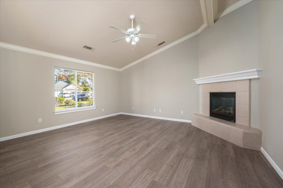 7704 Pit Road Redding, CA 96001 - Photo 8 of 34 an empty room with wooden floor chandelier and fireplace