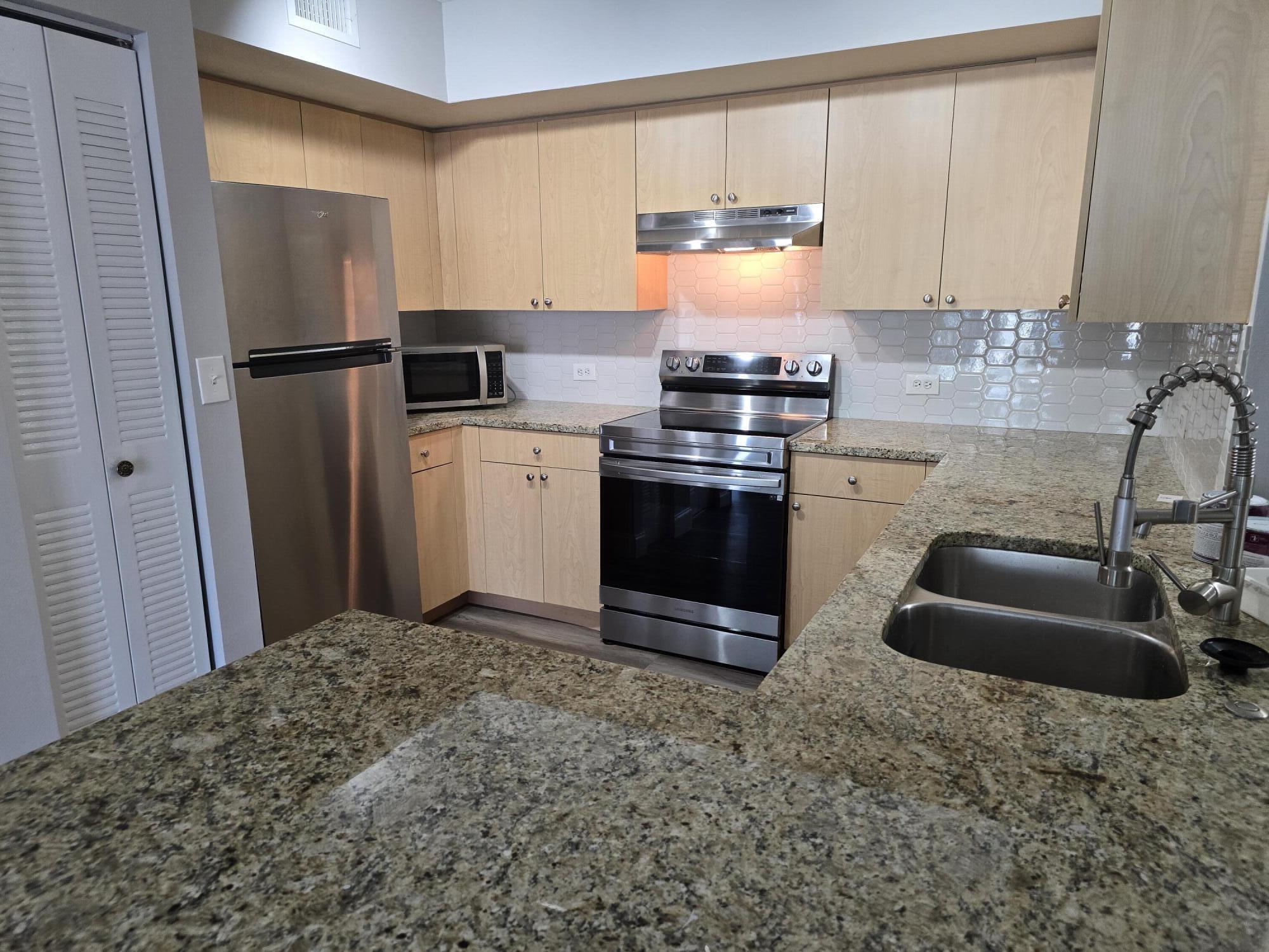 701 Villa Circle Boynton Beach, FL 33435 - Photo 3 of 17 a kitchen with stainless steel appliances granite countertop a sink stove and refrigerator