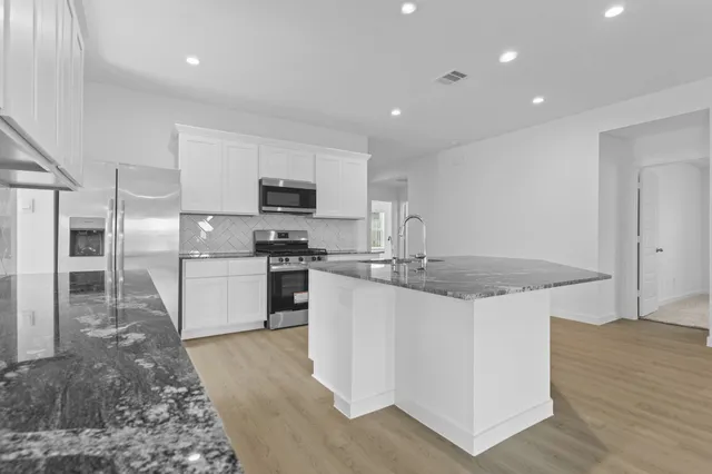 a kitchen with stainless steel appliances granite countertop a sink stove and refrigerator