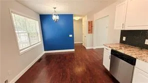 an empty room with wooden floor cabinet and windows