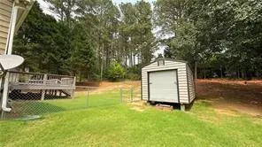 a view of a yard with wooden fence and large trees