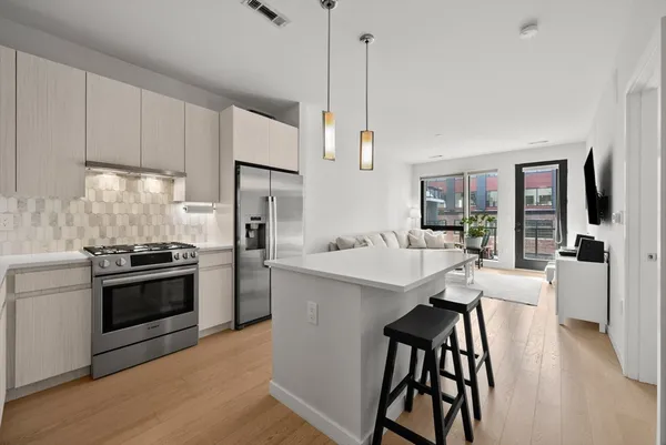 a kitchen with stainless steel appliances kitchen island a table chairs refrigerator and sink
