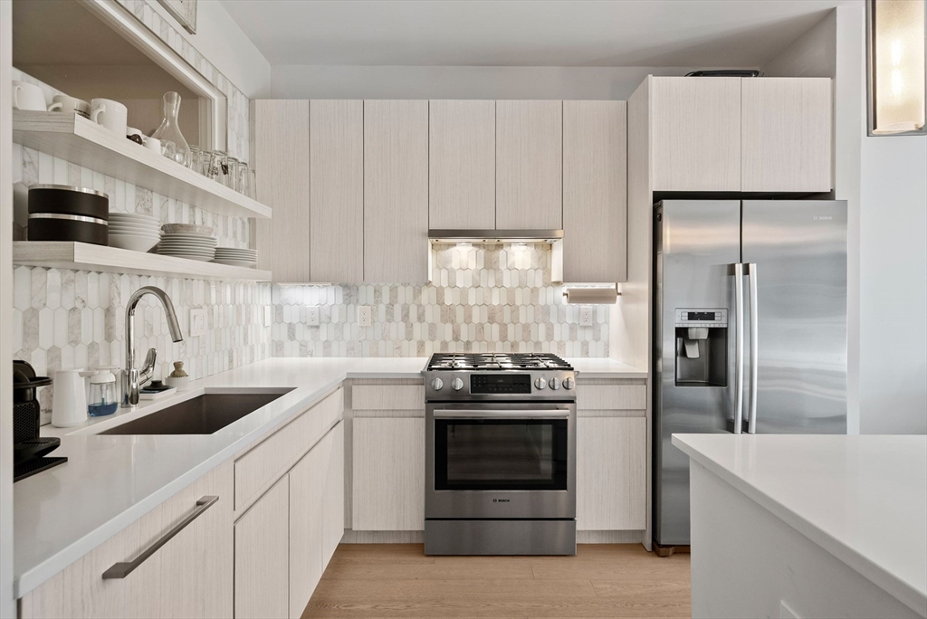45 West 3rd Street, Unit 406 Boston, MA 02127 - Photo 5 of 14 a kitchen with granite countertop white cabinets and stainless steel appliances