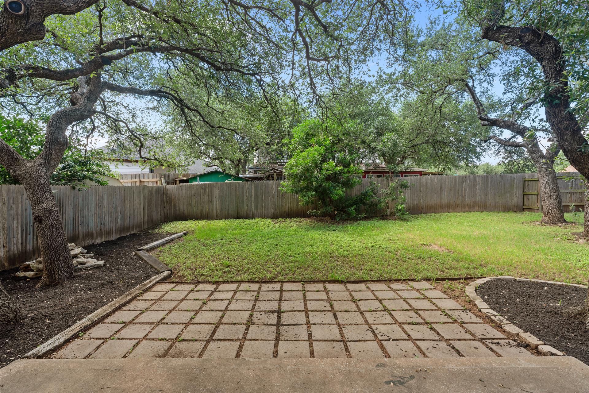 1710 Persimmon Road Cedar Park, TX 78613 - Photo 30 of 33 A generous backyard offers a private green oasis with mature trees and a checkered patio space - perfect for entertaining.