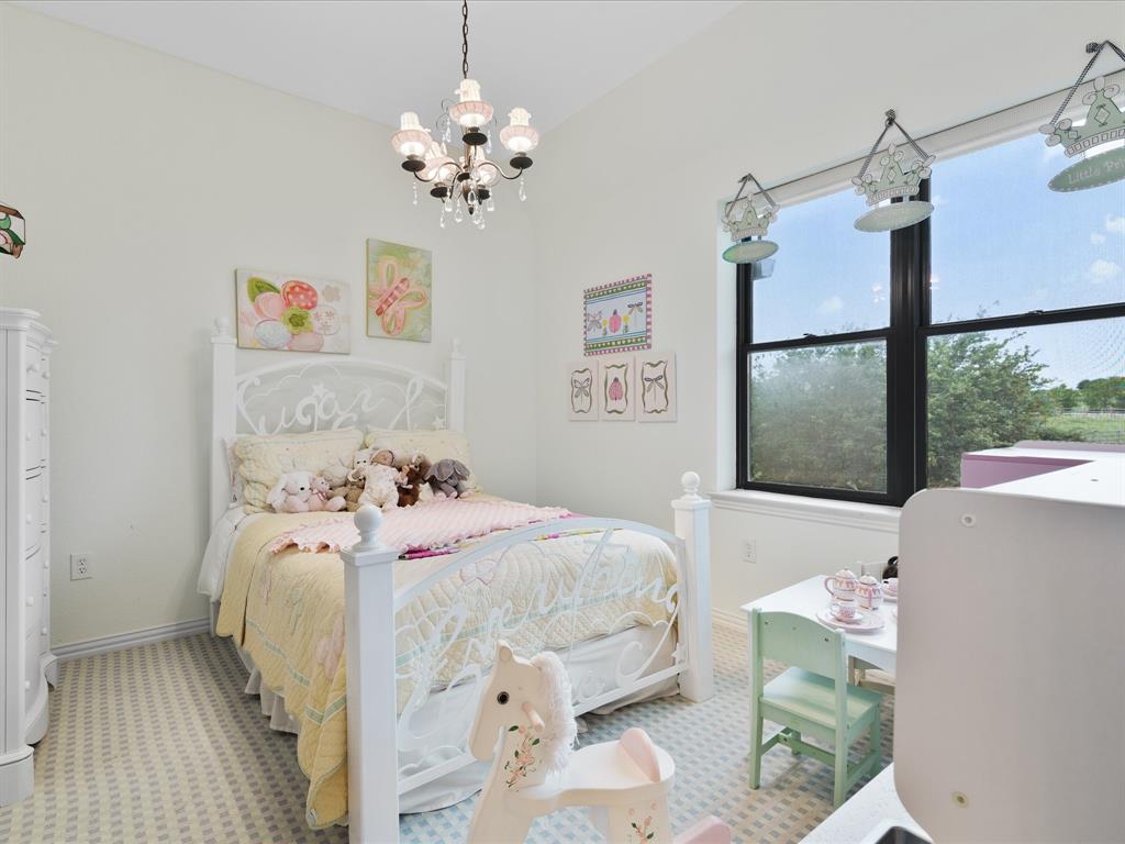 8970 Burnett Road Justin, TX 76247 - Photo 25 of 40 a bedroom with a bed and a chandelier