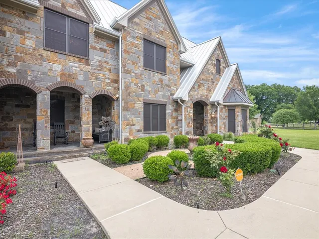 a view of a big house with a big yard and potted plants in front of the house