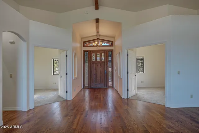 an empty room with wooden floor chandelier and a window