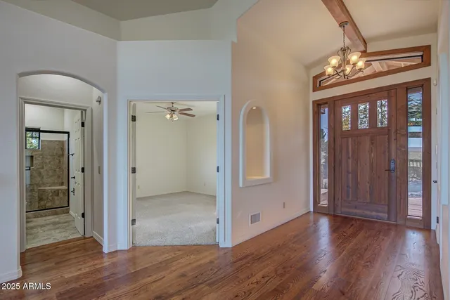 a view of a hallway with wooden floor and a chandelier
