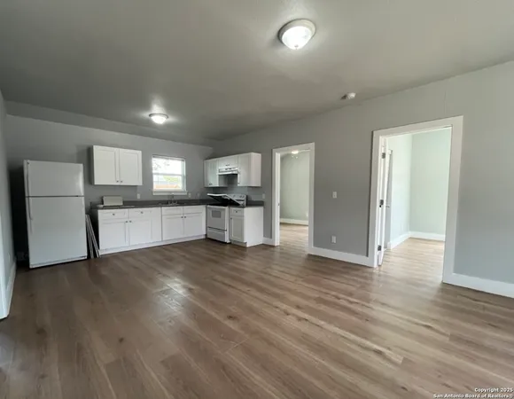 a view of a kitchen with a sink and dishwasher a refrigerator with wooden floor