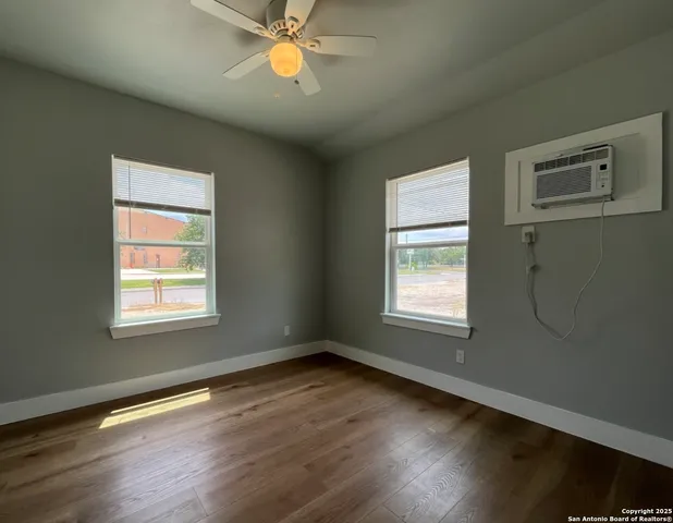 a view of an empty room with wooden floor and a window