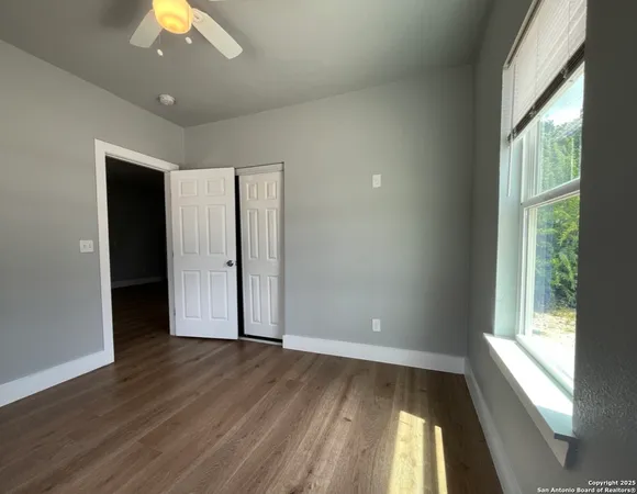 an empty room with wooden floor and windows