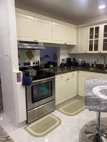 a kitchen with granite countertop a stove a sink and a microwave