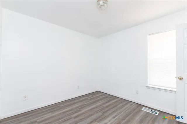 a view of a small space with wooden floor and a window