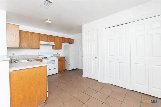 a kitchen with a sink a stove a refrigerator and cabinets
