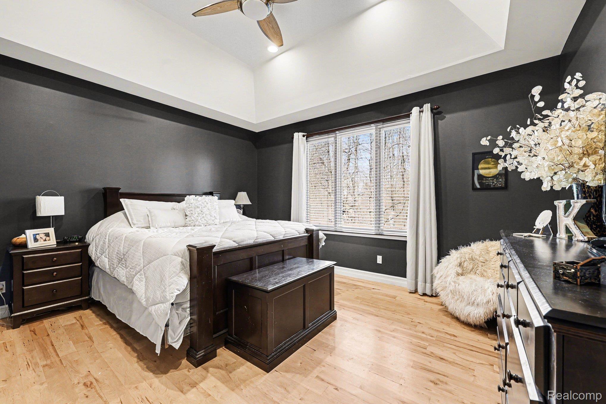 55256 Lee Road New Hudson, MI 48165 - Photo 14 of 28 Bedroom featuring light wood-style flooring, a ceiling fan, and a tray ceiling
