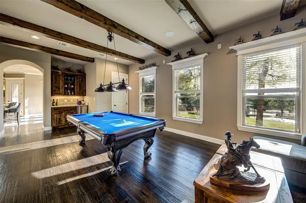 a room with furniture pool table wooden floor and windows