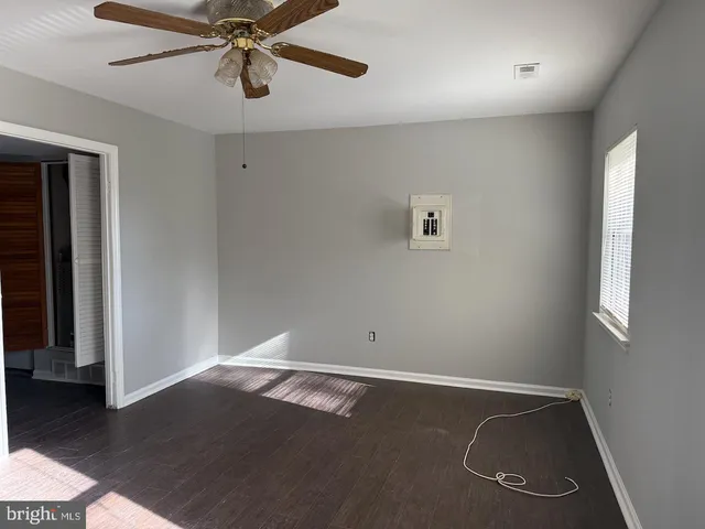 an empty room with wooden floor closet fan and windows