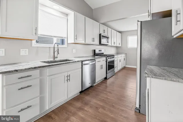 a kitchen with granite countertop white cabinets and white stainless steel appliances