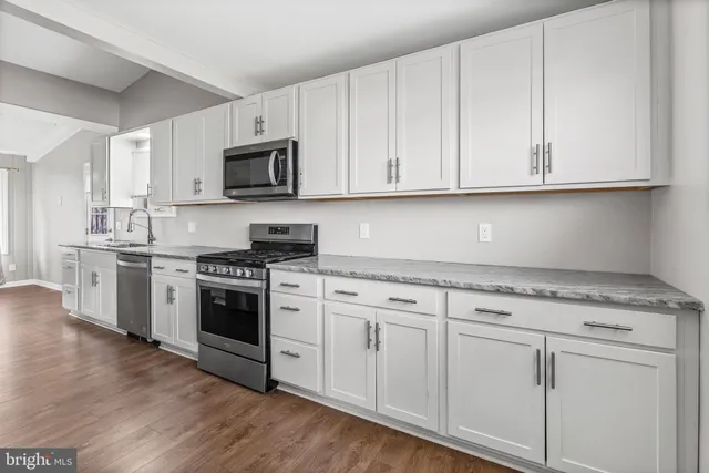 a kitchen with granite countertop white cabinets and stainless steel appliances