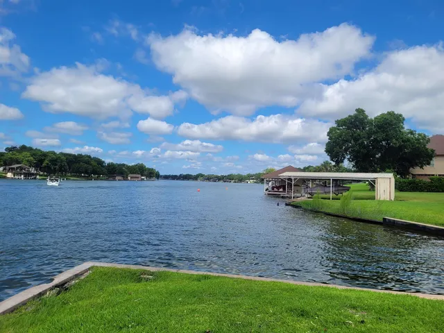 a view of a lake with a big yard and large trees