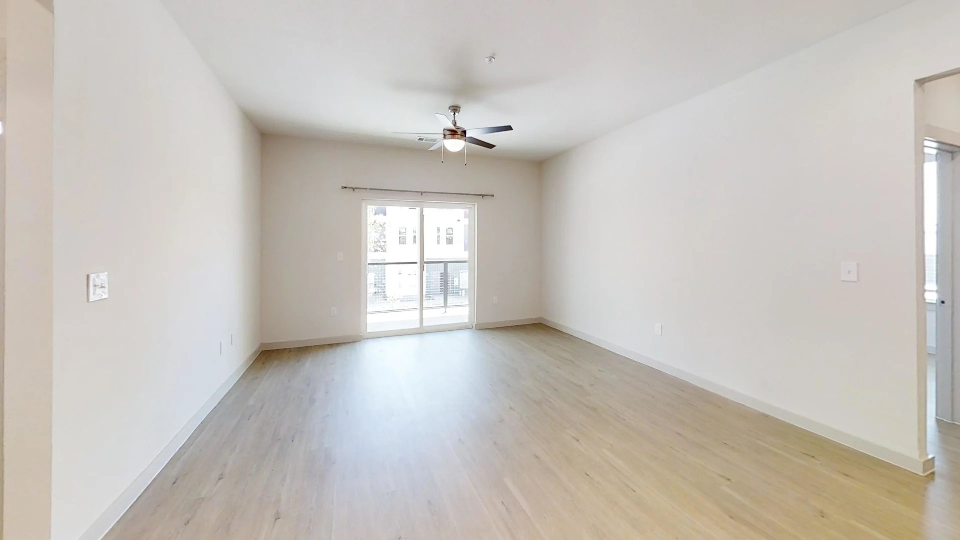 320 Goll Street, Unit 3207 Kyle, TX 78640 - Photo 13 of 19 an empty room with wooden floor chandelier fan and windows