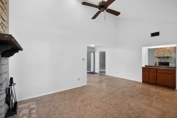 an empty room with windows and fireplace