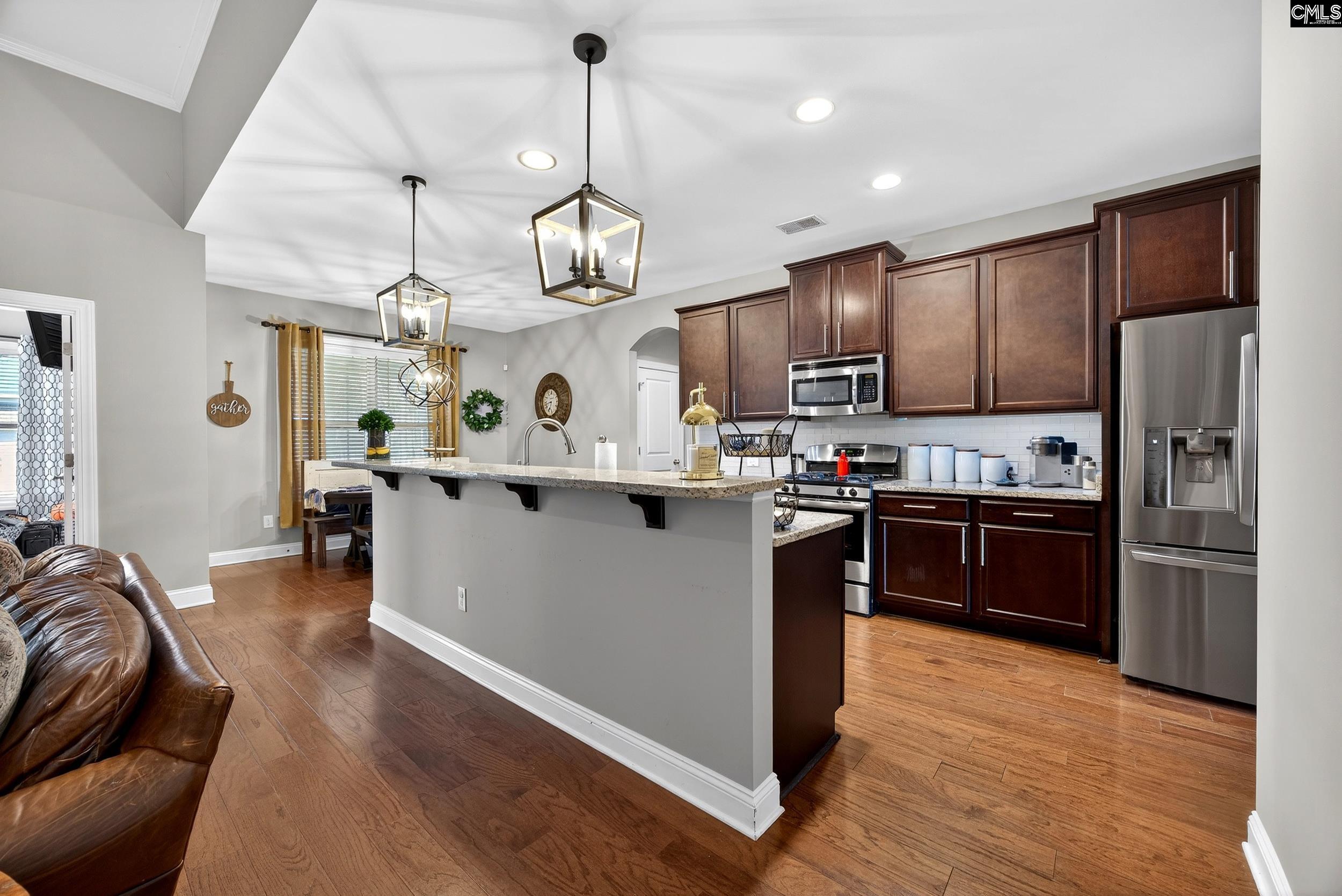 116 Renard Way Gilbert, SC 29054 - Photo 27 of 74 a kitchen with stainless steel appliances kitchen island granite countertop a refrigerator a stove top oven a sink dishwasher and a dining table with wooden floor