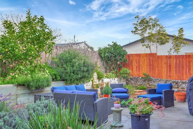 a patio with couches table and chairs and potted plants