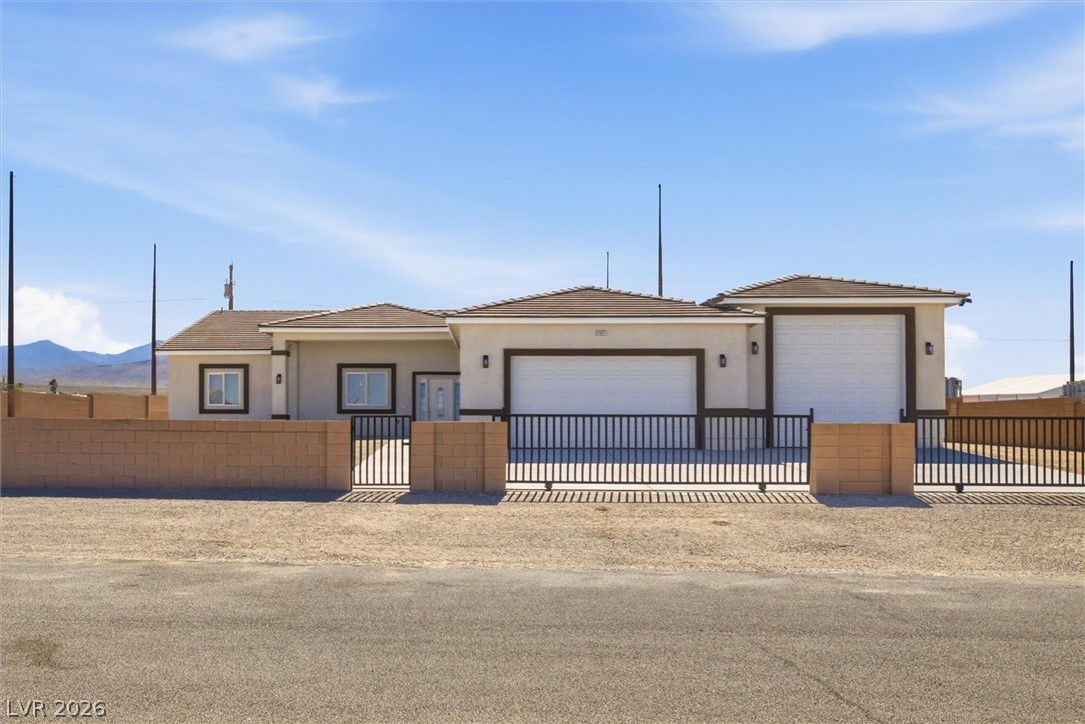 1061 Factory Road Pahrump, NV 89048 - Photo 1 of 41 Secure desert oasis featuring an attached garage, a sturdy gate, and mountain views.