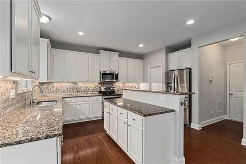a kitchen with granite countertop white cabinets stainless steel appliances and a sink