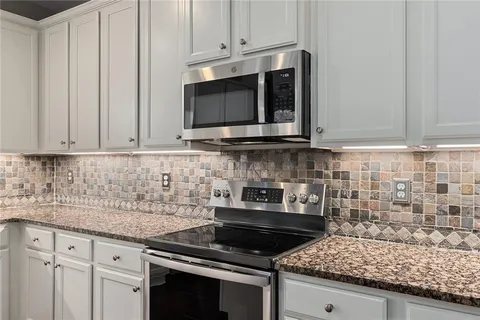a kitchen with granite countertop white cabinets and a window