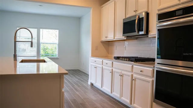 a kitchen with stainless steel appliances granite countertop a stove a sink and a microwave