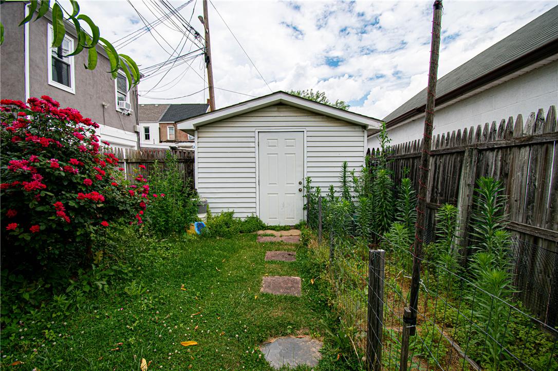 27 West Allen Street Allentown, PA 18102 - Photo 26 of 26 A quaint backyard shed, bordered by a wooden fence and vibrant rose bushes, offers practical outdoor storage.