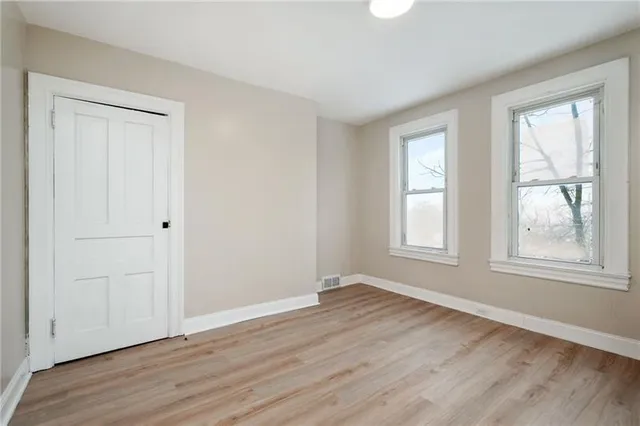 an empty room with wooden floor and windows