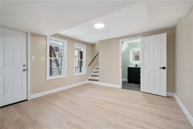 a view of an empty room with a window and wooden floor