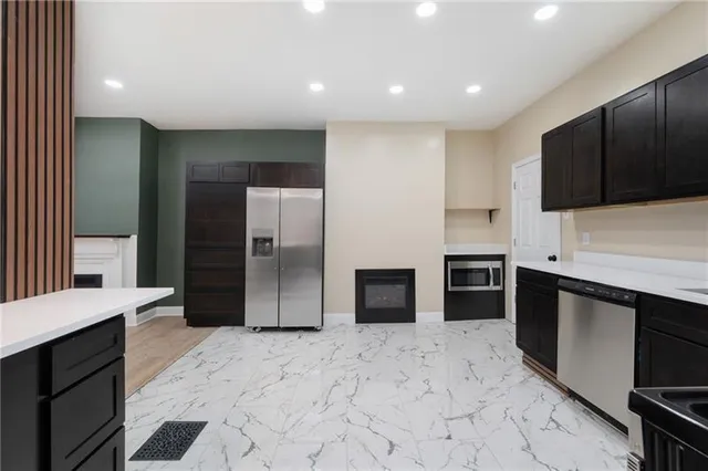 a kitchen with stainless steel appliances kitchen island granite countertop a refrigerator and a sink