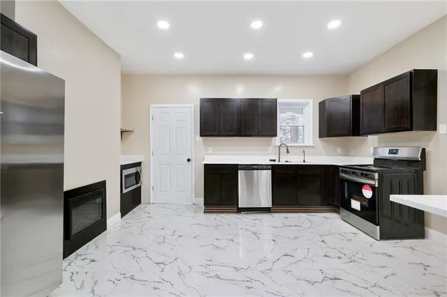a kitchen with stainless steel appliances kitchen island granite countertop a stove a sink and a refrigerator