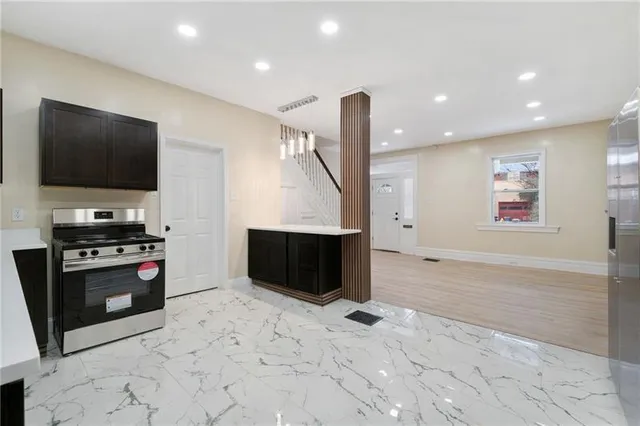 a kitchen with stainless steel appliances a stove and a flat screen tv